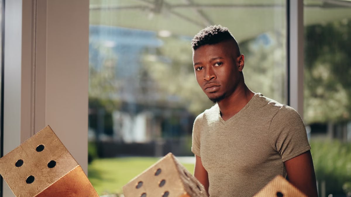 Indoor portrait of a man in a casual V-neck shirt beside large decorative dice.